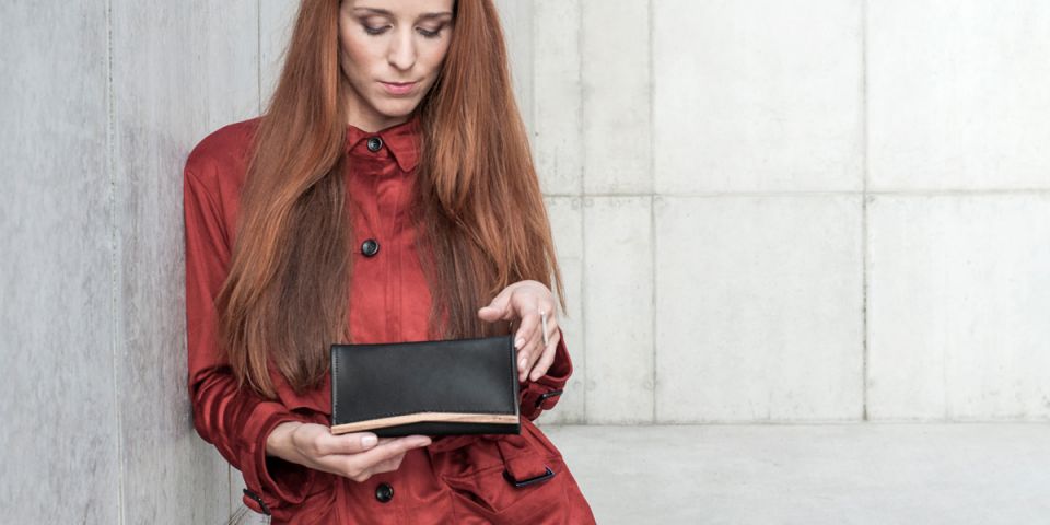 Ruda kobieta w pomarańczowym płaszczu, trzymająca skórzany portfel Api Woman Wallet Ruda kobieta w pomarańczowym płaszczu, trzymająca skórzany portfel Api Woman Wallet
