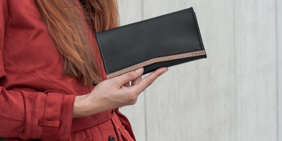 Ruda kobieta w pomarańczowym płaszczu, trzymająca skórzany portfel Caleo Woman Wallet Ruda kobieta w pomarańczowym płaszczu, trzymająca skórzany portfel Caleo Woman Wallet